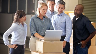 Employees in warehouse looking computer